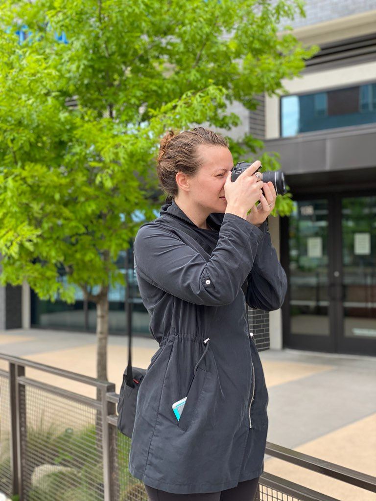 Mindy Herb shooting on location with a DSLR camera raised to her eye.