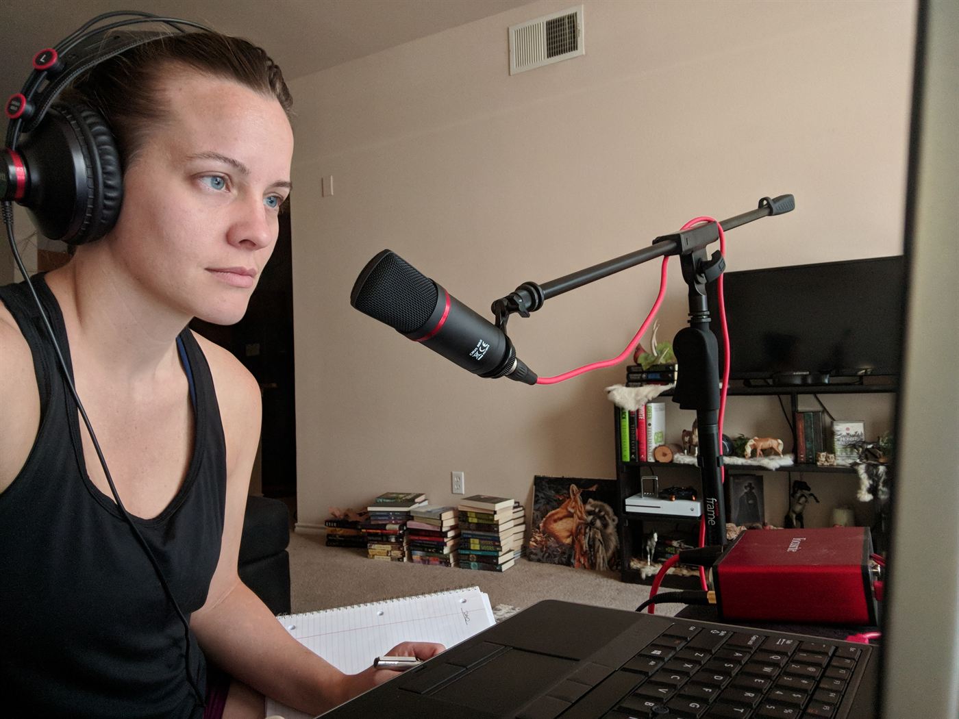 Mindy Herb wearing headphones at a laptop with a boom-mounted microphone, working a remote session.